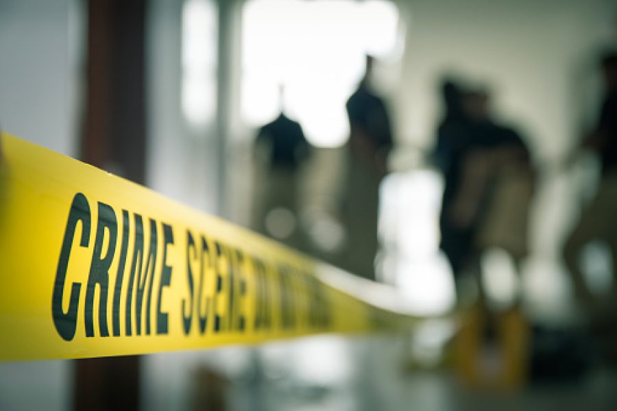 crime scene tape with blurred forensic law enforcement background in cinematic tone and copy space